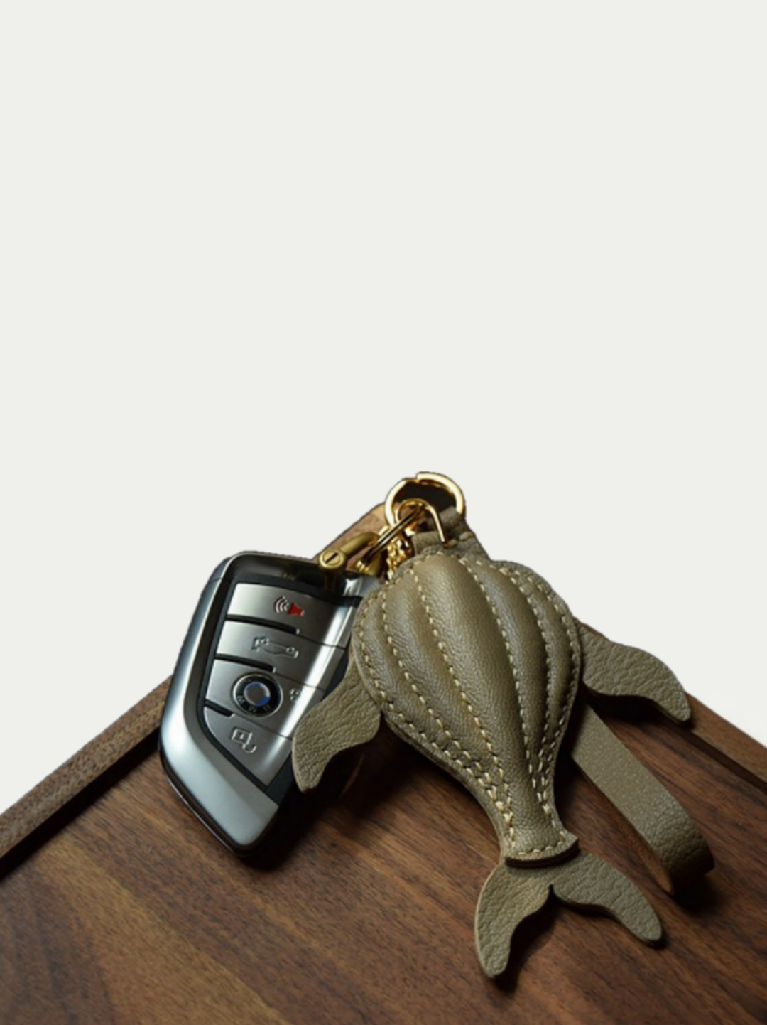 Ocean brown whale leather charm hanging from a cream handbag

